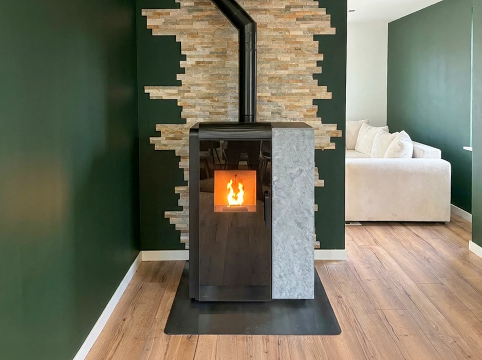 Poêle à granulés design en coin, paroi verte foncée avec parement en pierre naturelle stratifiée beige