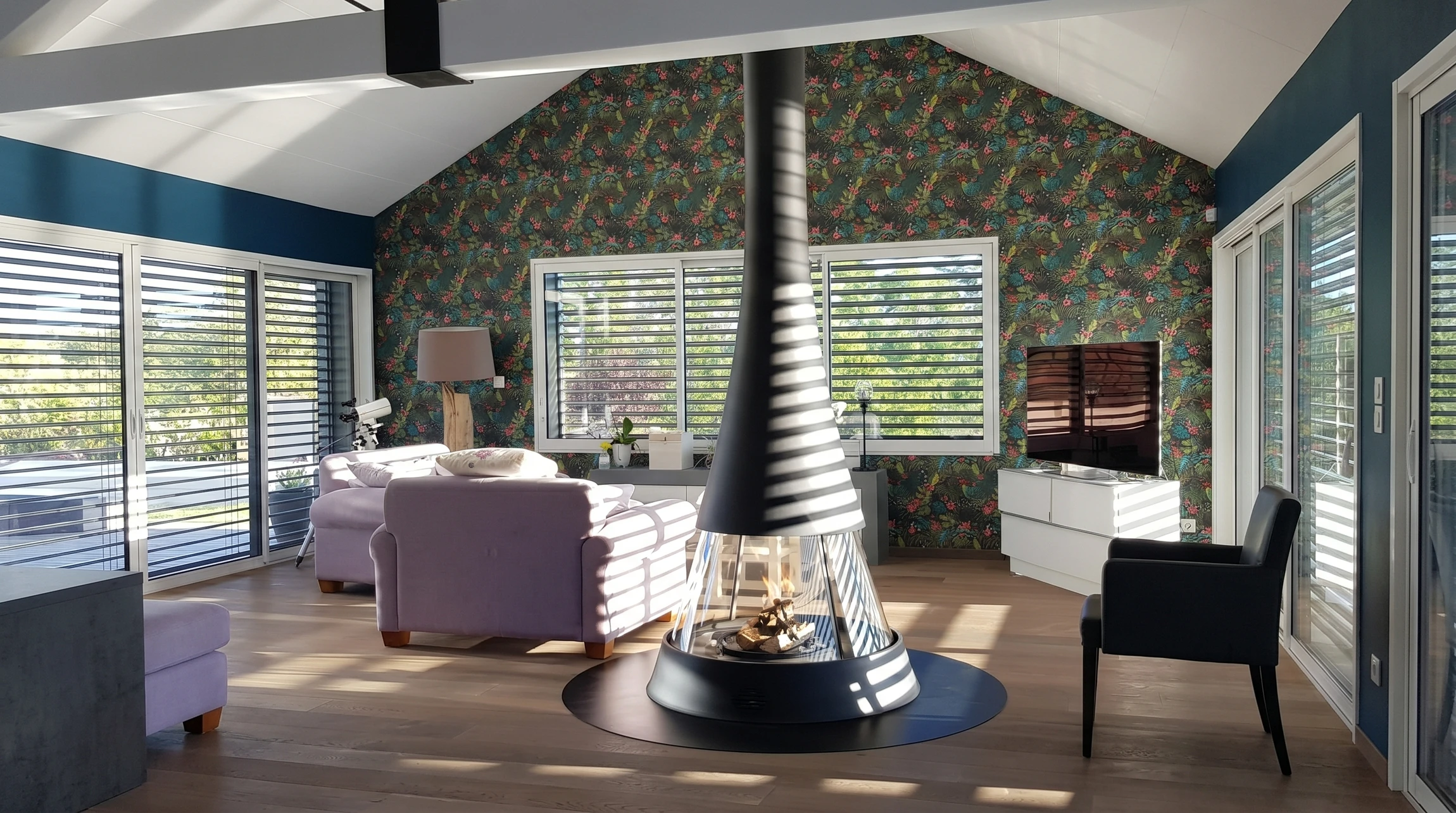 Intérieur contemporain avec cheminée design ovale noire suspendue, feu allumé visible