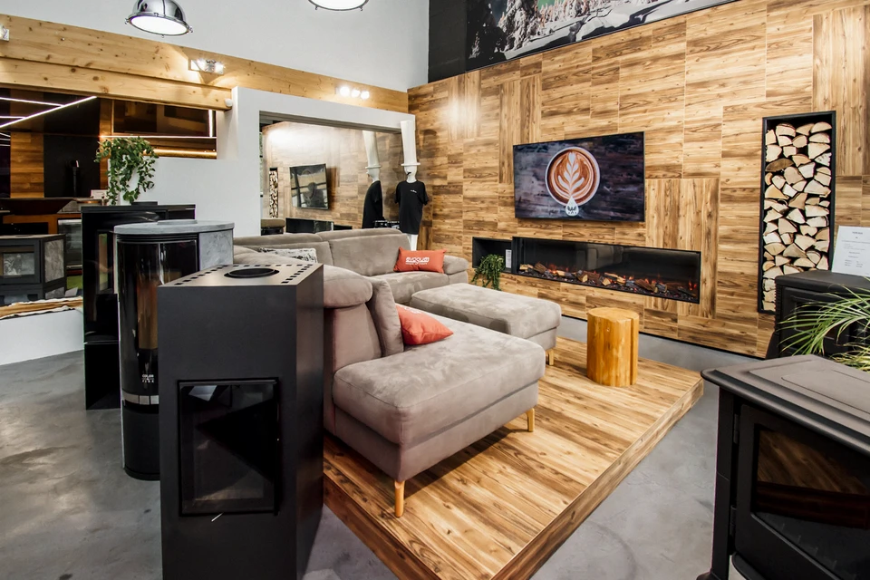 Salon moderne avec cheminée à foyer ouvert en fonctionnement, canapés beiges disposés en L, parquet chevron, tapis rond tressé naturel
