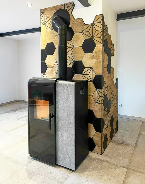 Intérieur chalet, poêle à bois design installé devant un mur en parement pierre naturelle stratifiée
