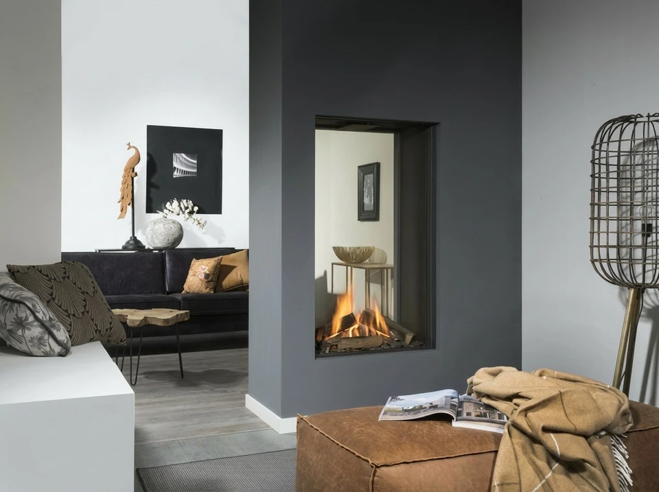 Salon de luxe avec cheminée à gaz en fonctionnement, canapés gris et fauteuils beiges disposés autour d'une table basse
