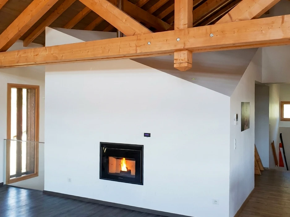 Poêle à granulés design en coin, paroi verte foncée avec parement en pierre naturelle stratifiée beige