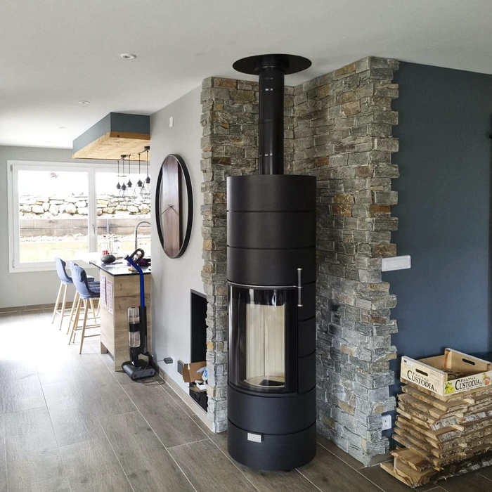 Intérieur moderne avec poêle à bois design noir et gris pierre, installé devant un habillage mural en carreaux hexagonaux dorés à motifs géométriques Asanoha noirs