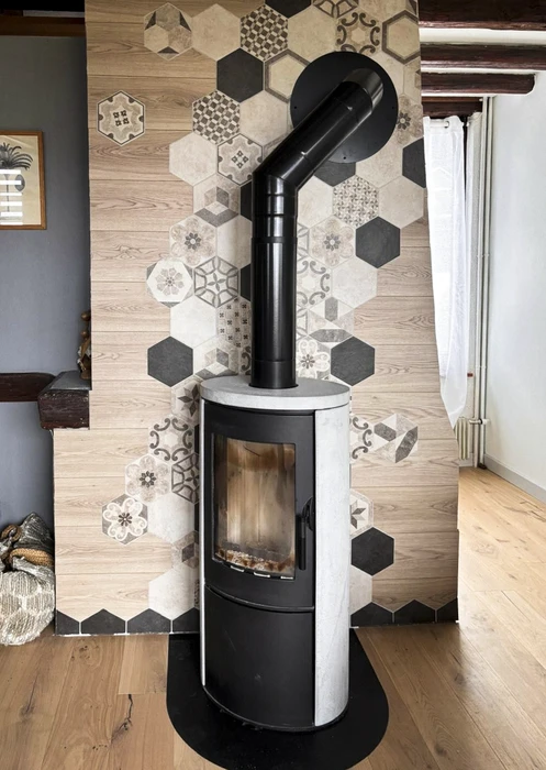 Poêle à bois central suspendu, design contemporain, corps cylindrique en acier noir mat avec foyer panoramique vitré 270°, flammes vives visibles