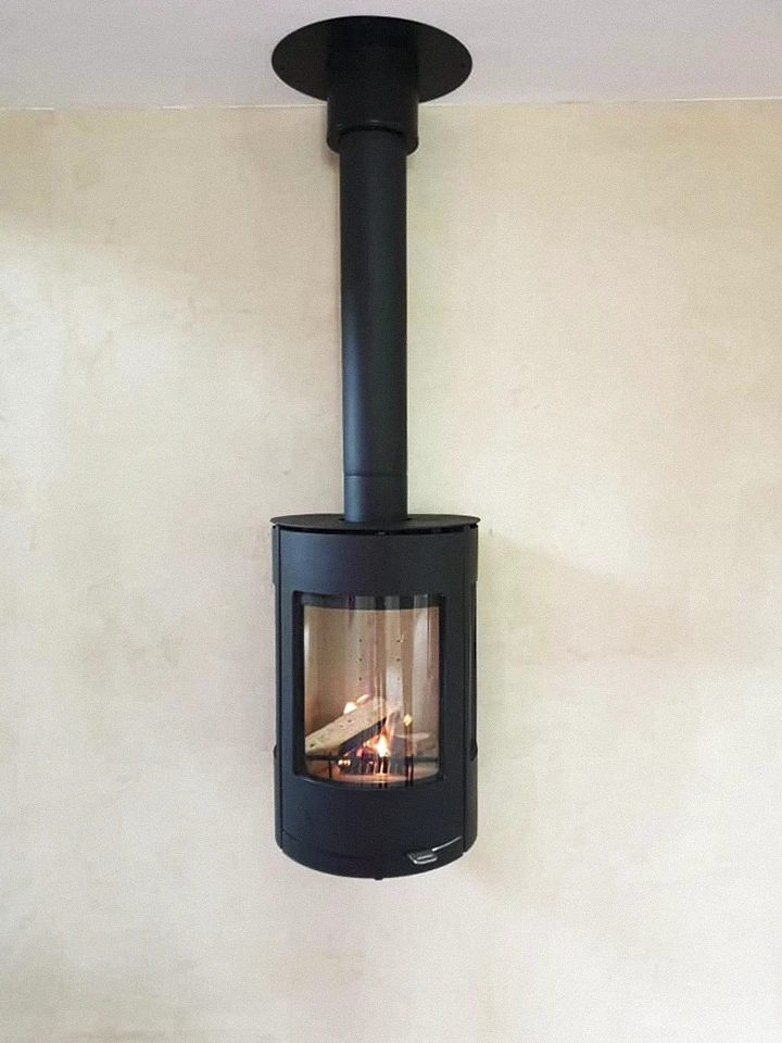 Intérieur moderne, poêle à bois cylindrique en stéatite grise avec insert vitré, flammes vives visibles